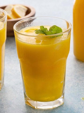 two glasses filled with yellow lemonade.