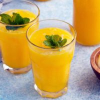 glasses filled with mango lemonade and garnished with mint.