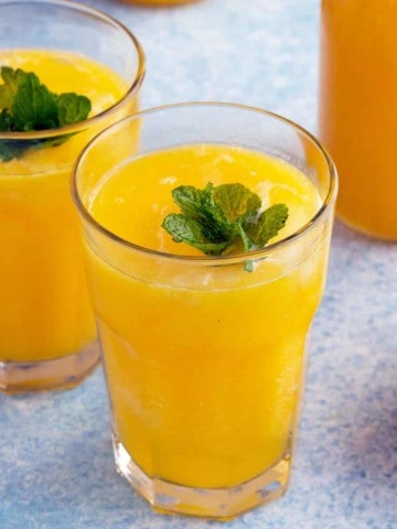 glasses filled with mango lemonade and garnished with mint.