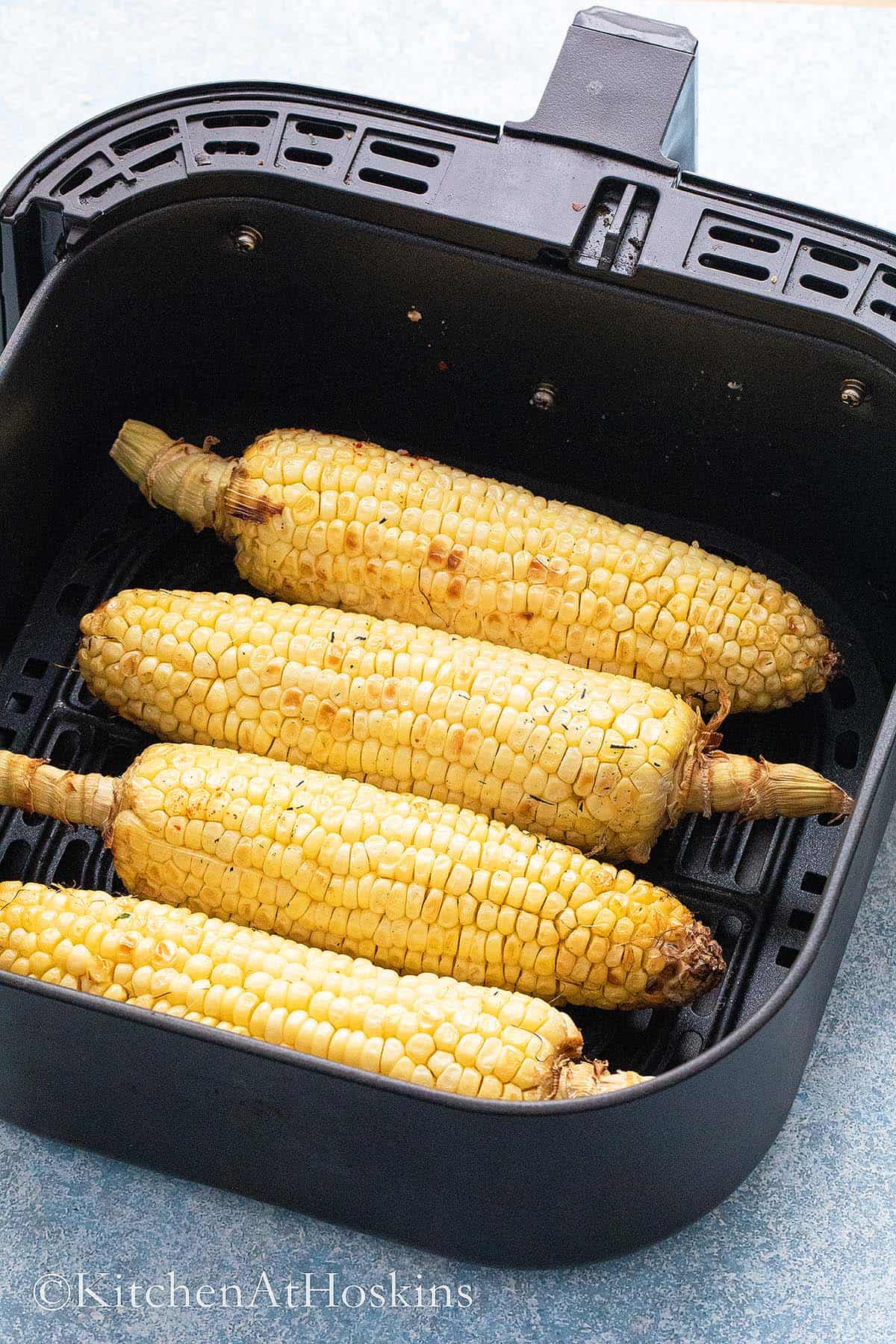 roasted corn on the cobs in a air fryer basket.