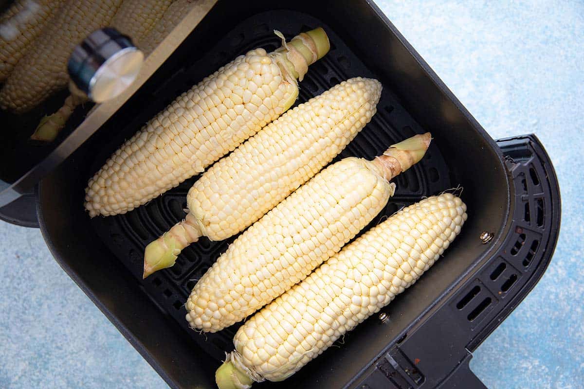 Air fry corn on the cob in husk 3 corn on the cob in air fryer basket.