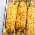 roasted corn on the cob on a white tray.