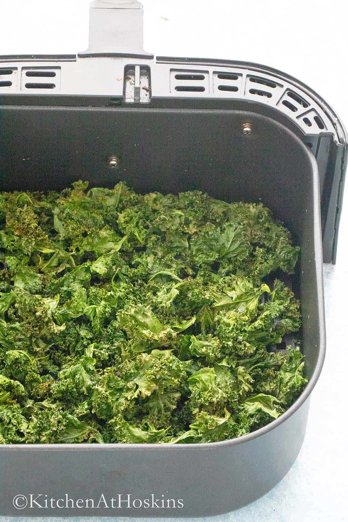 crispy kale chips in an air fryer basket.
