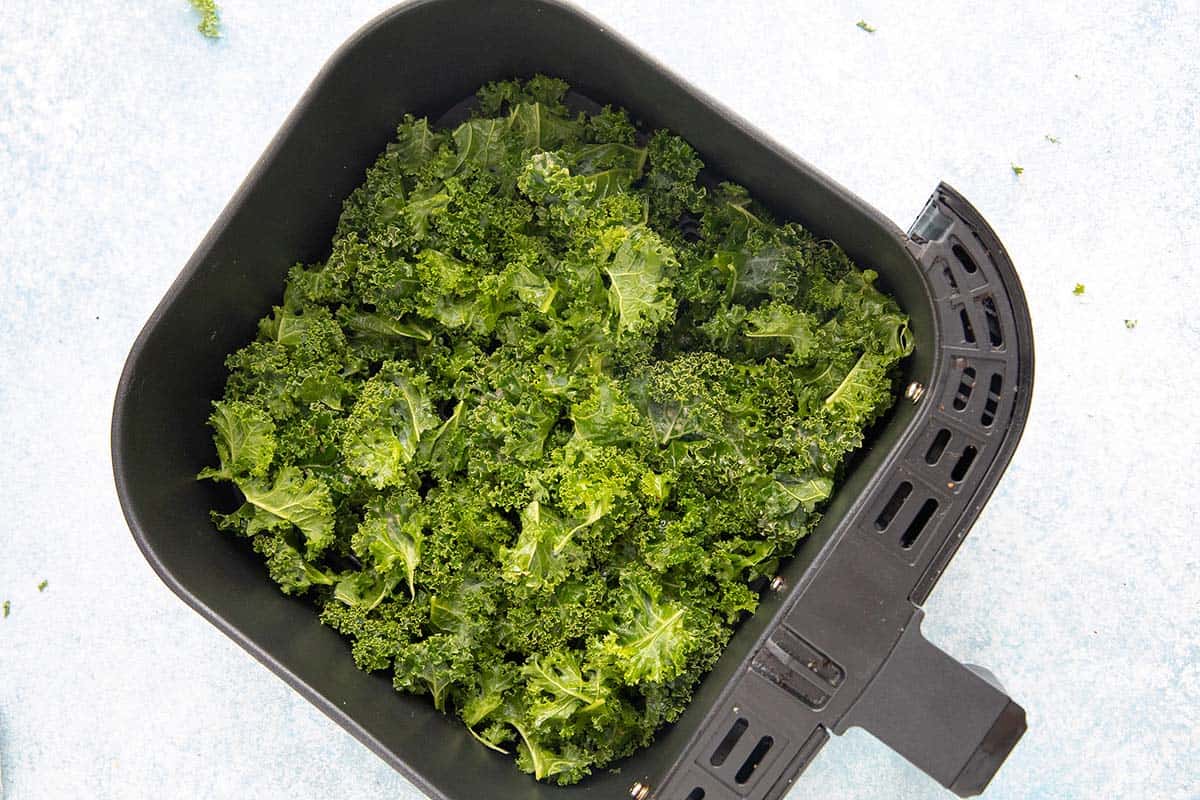 kale in an air fryer basket.