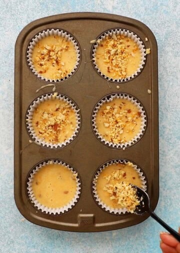 orange muffin batter filled in a 6 cup metal muffin pan.