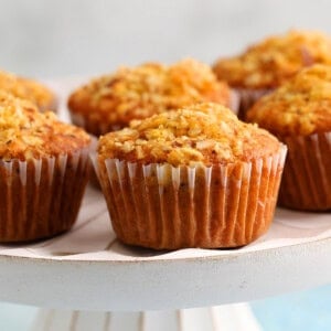 6 orange muffins placed on a white cake stand.