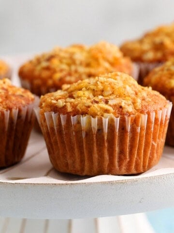 6 orange muffins placed on a white cake stand.