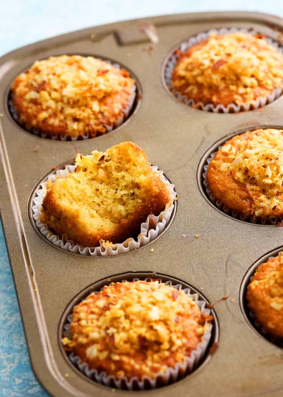 6 baked orange muffins in a metal muffin pan.