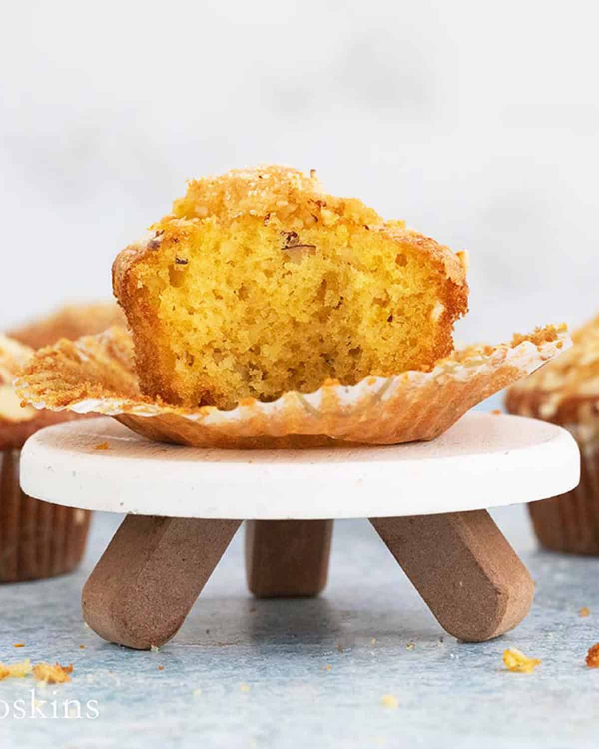 one half orange muffin placed on a small white cake stand with 3 brown legs.