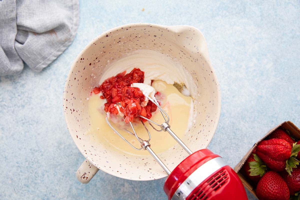condensed milk, strawberry pulp and whipped cram in a bowl. 