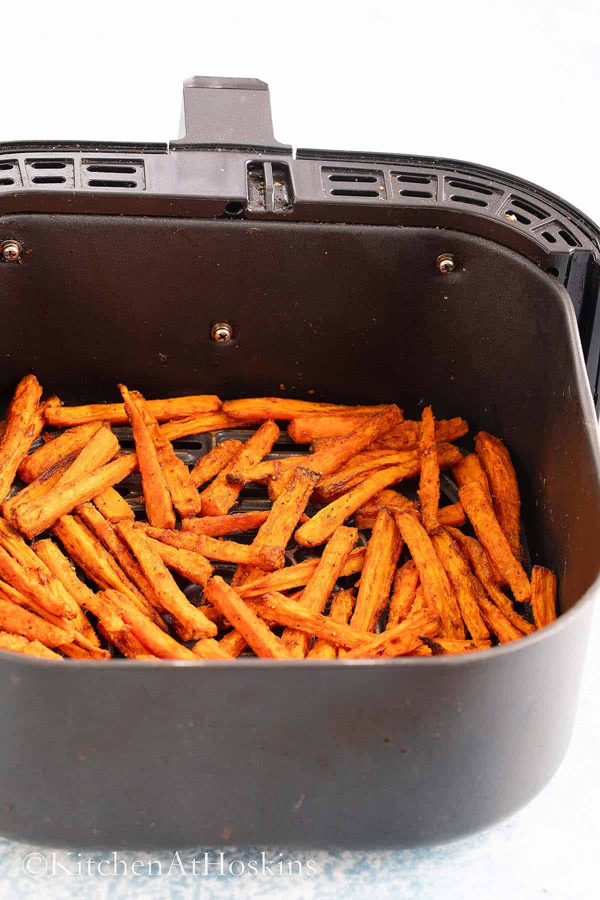 air fryer basket with cooked carrot fries.