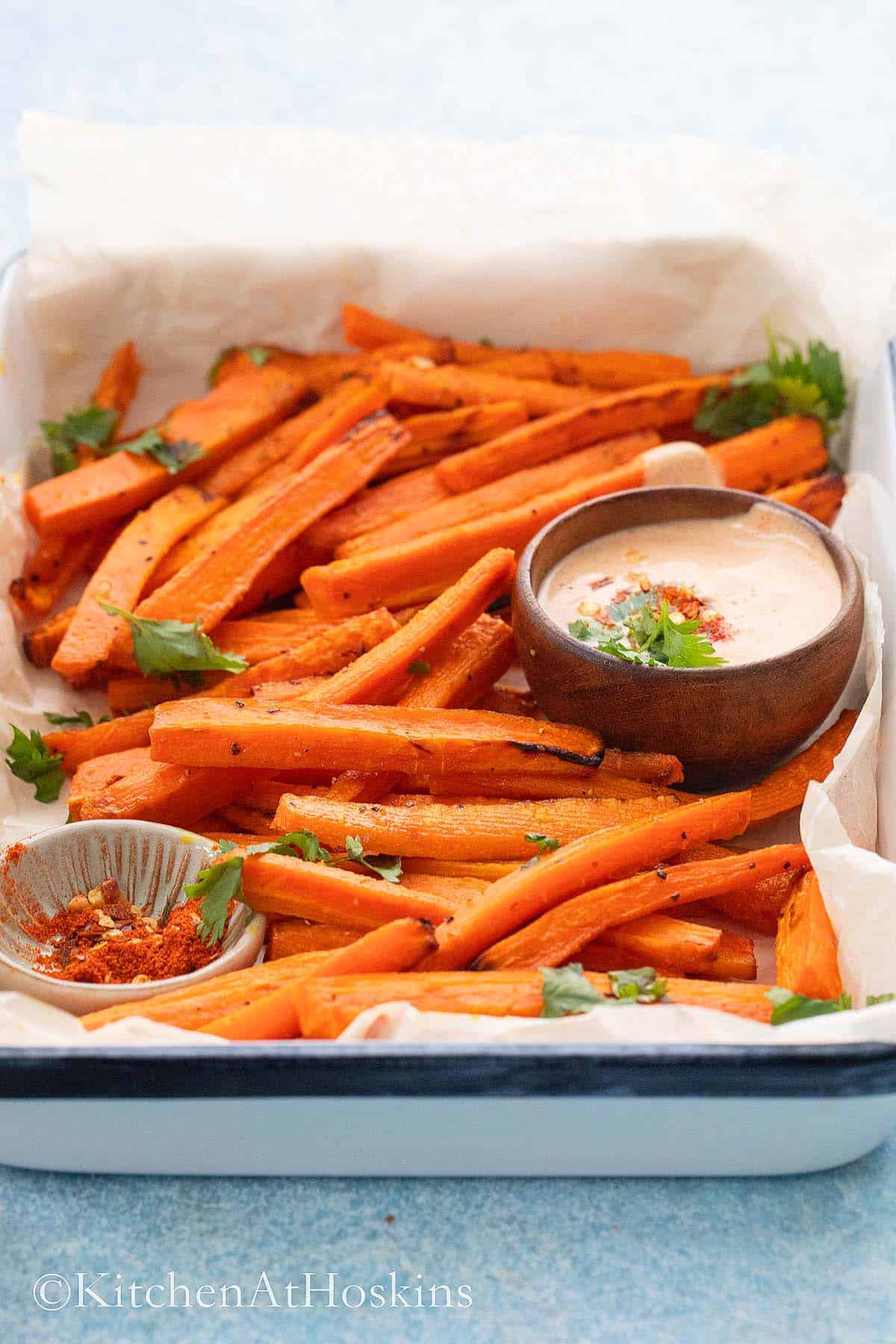 carrot fries on a white platter with sauce for dipping.