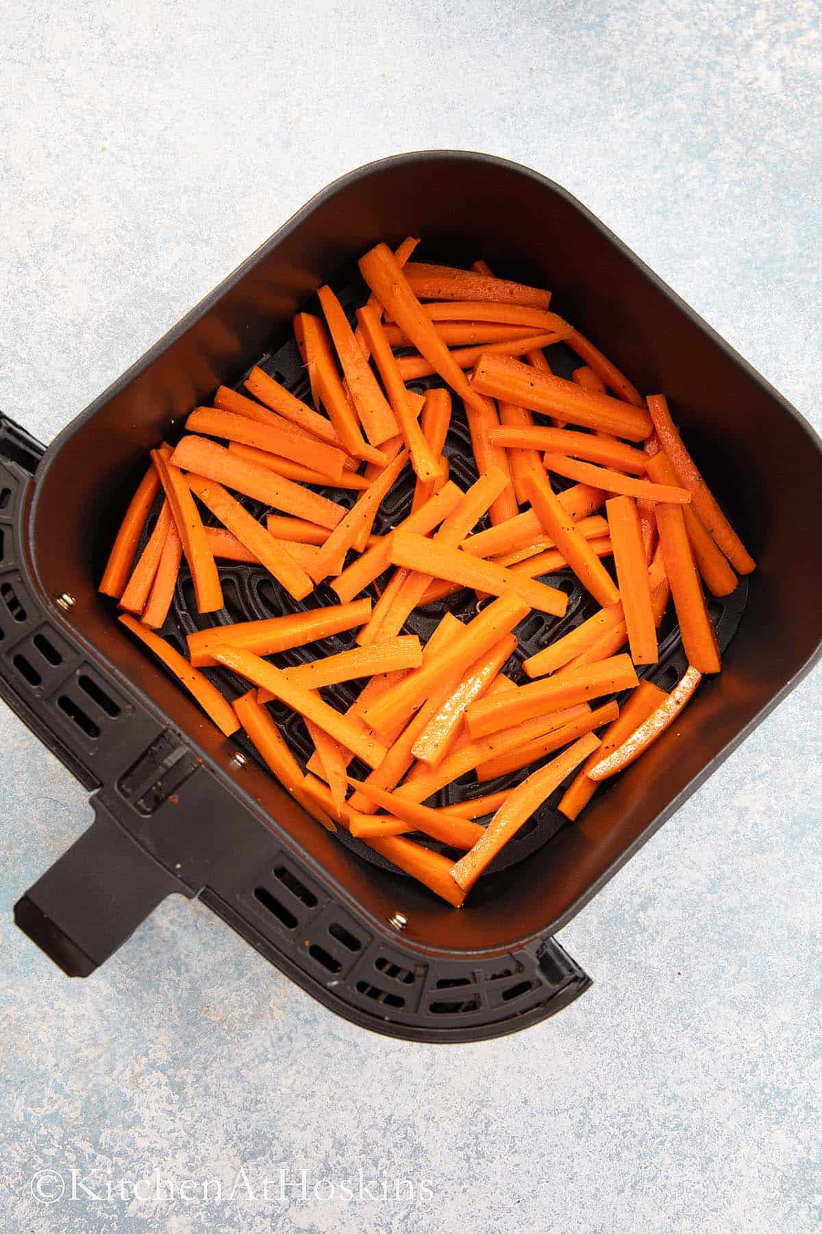 cut carrot sticks in an air fryer basket.