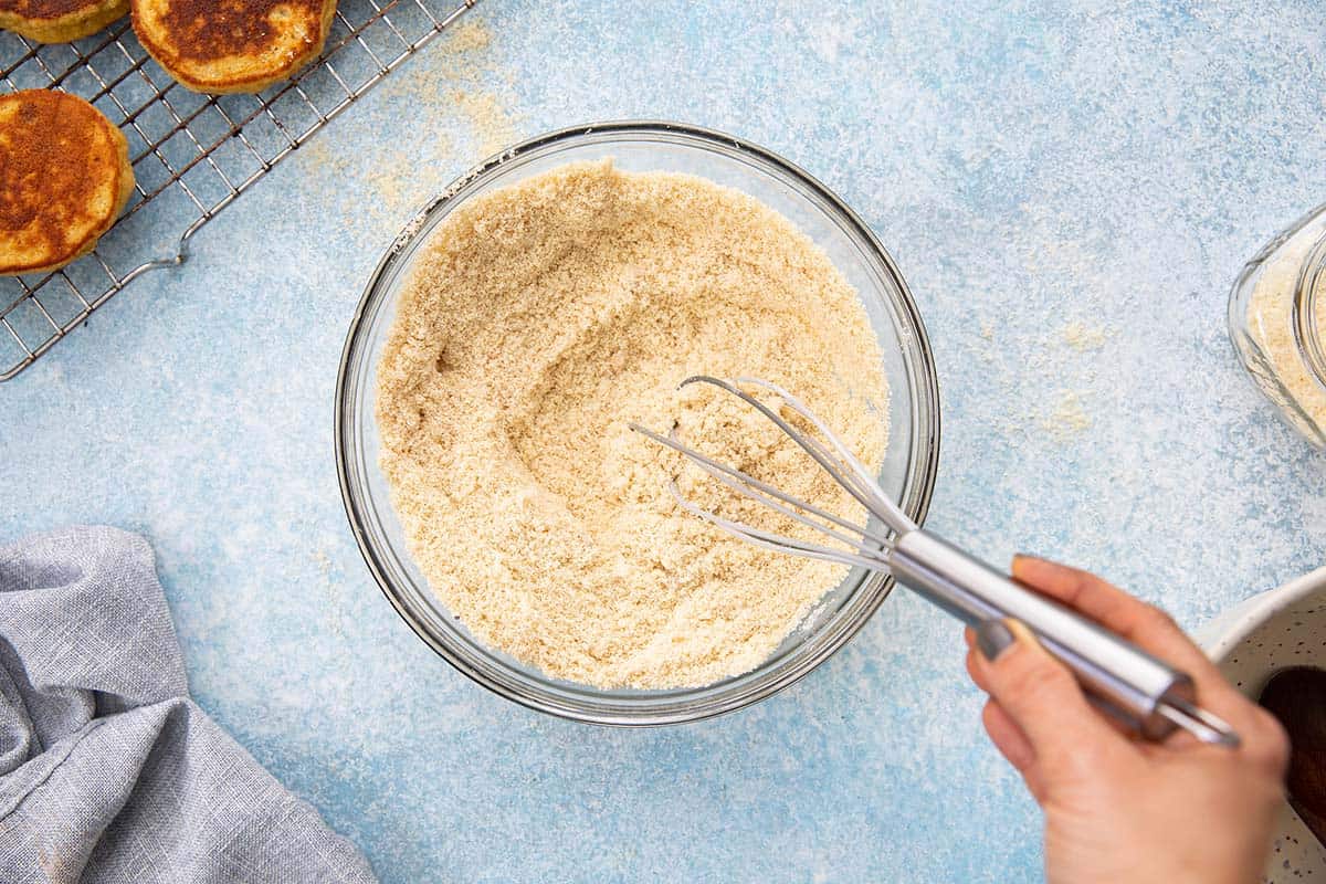 WHISKING ALMOND FLOUR IN A GLASS BOWL. 