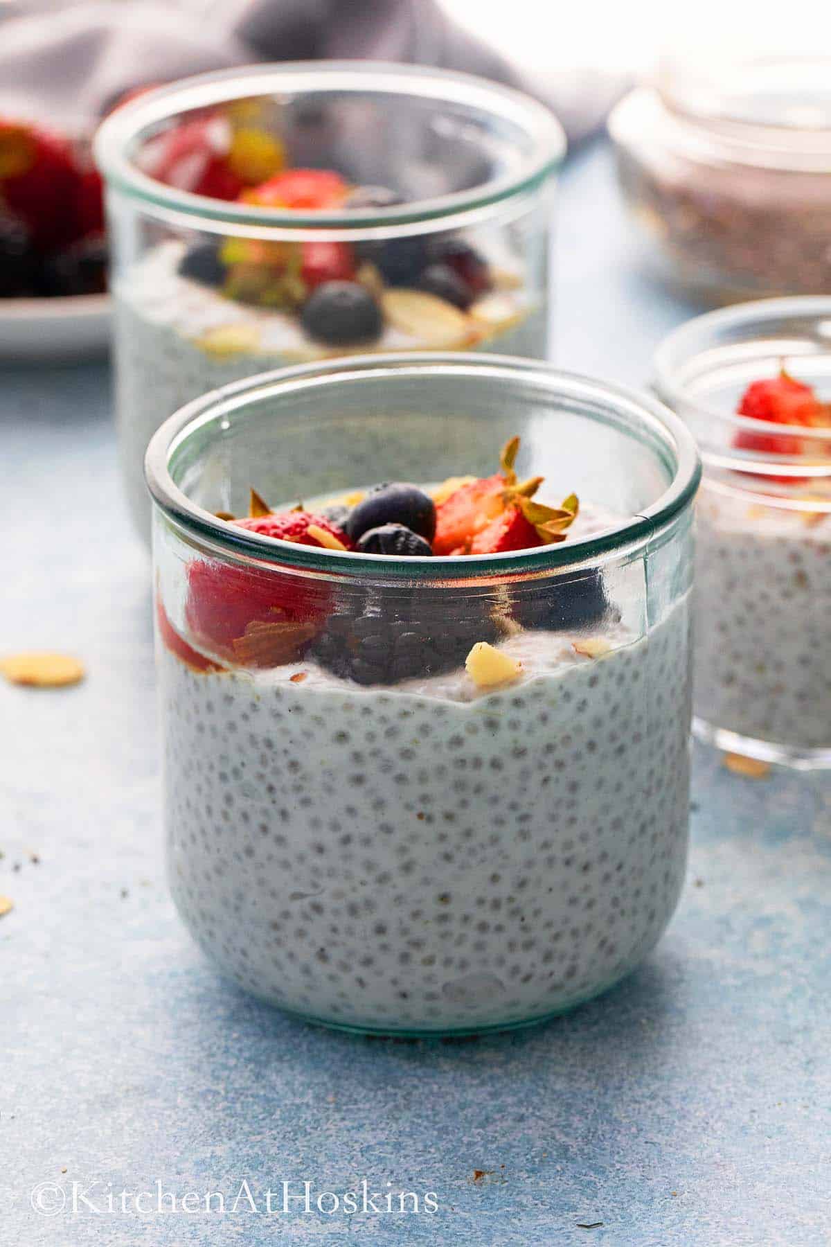 glass jars with coconut chia seed pudding topped with berries.