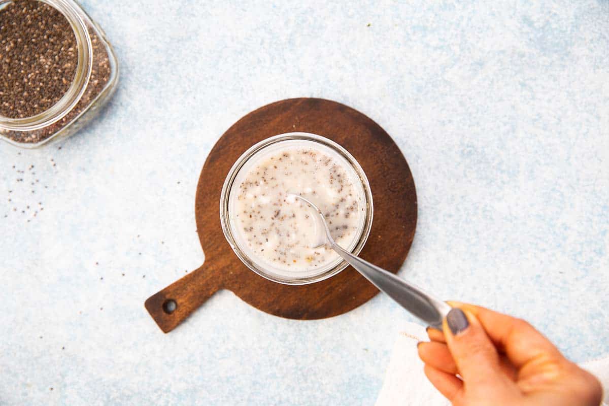 stirring coconut milk with chia seeds in a jar.