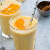 orange smoothie in glasses with straws.