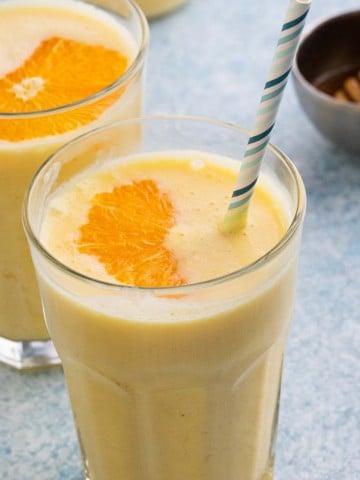 orange smoothie in glasses with straws.