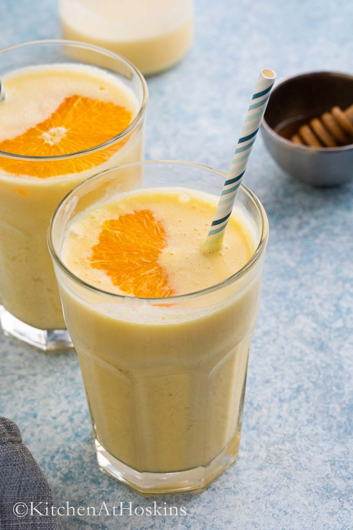 glasses with healthy orange smoothie and garnished with orange slice.