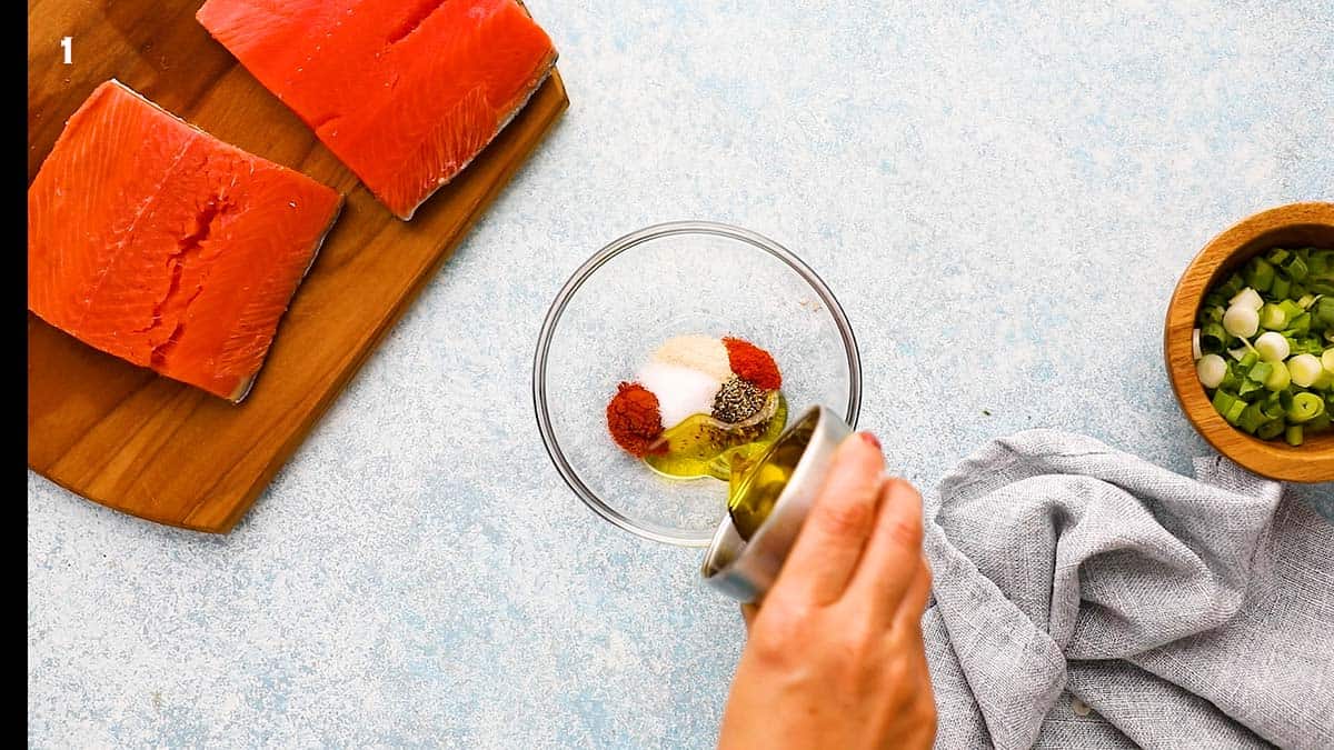 pouring olive oil into a small glass bowl with spices.