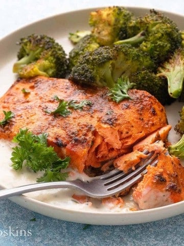 air fried salmon on a white plate with broccoli along with a fork.