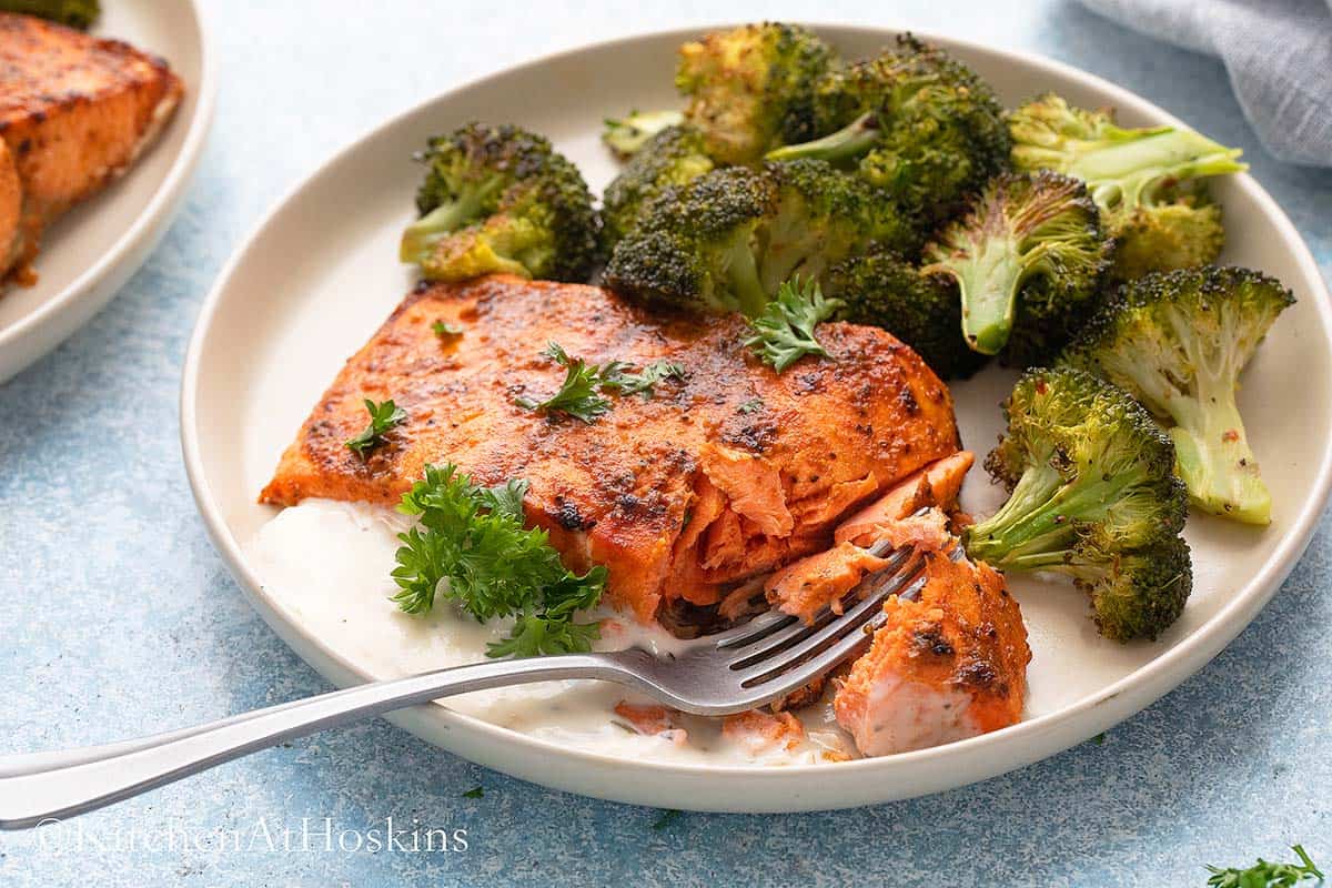 white plates with cooked spicy salmon and broccoli.