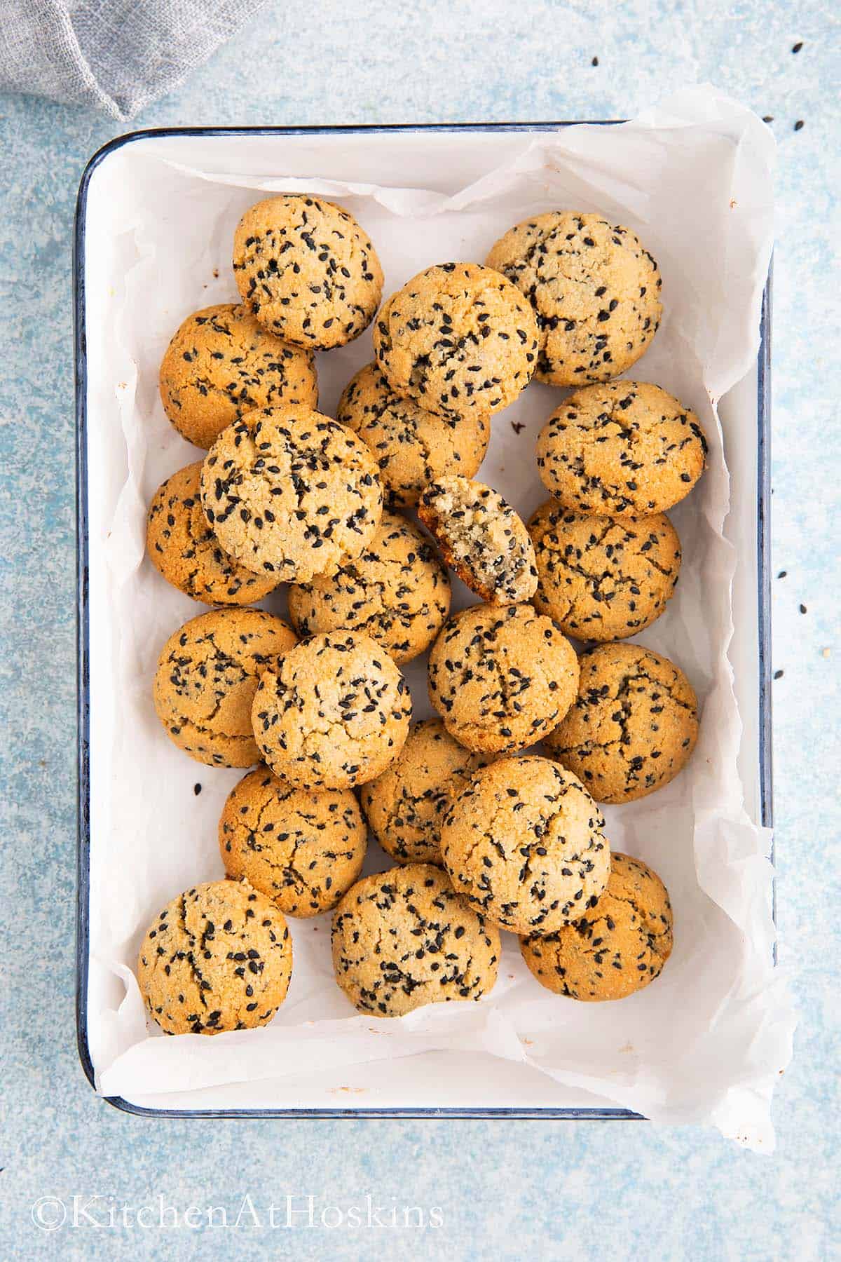 black sesame cookies on a parchment lined white tray.