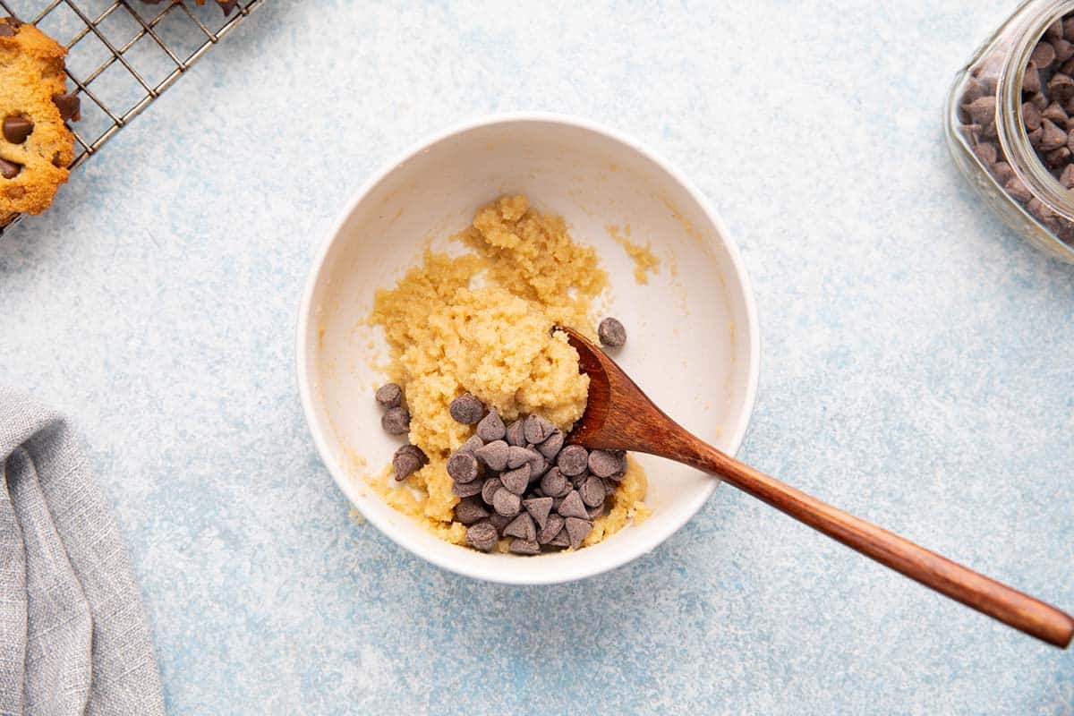 cookie dough with chocolate chips in a small bowl with wooden spoon. 