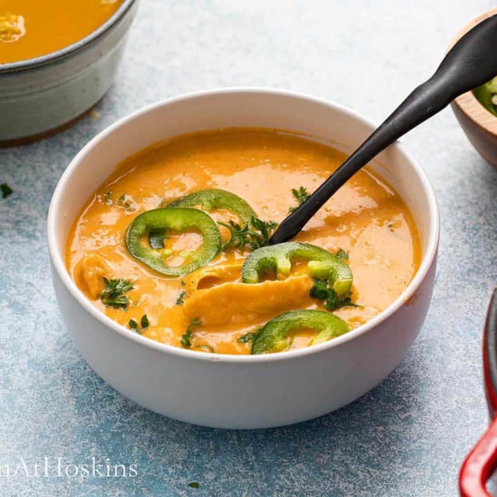 creamy chicken rice soup in a bowl with a black spoon.