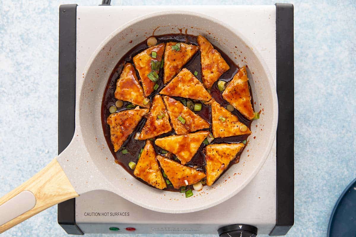 cooked tofu in a frying pan placed on a stove.