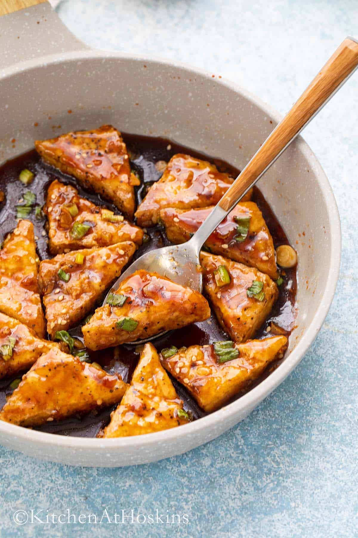 white skillet with cooked tofu in teriyaki sauce.