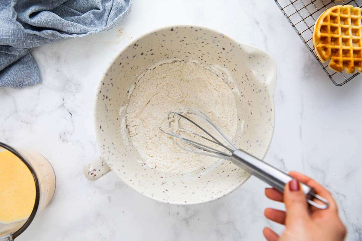 whisking dry ingredients in a bowl with a whisk.