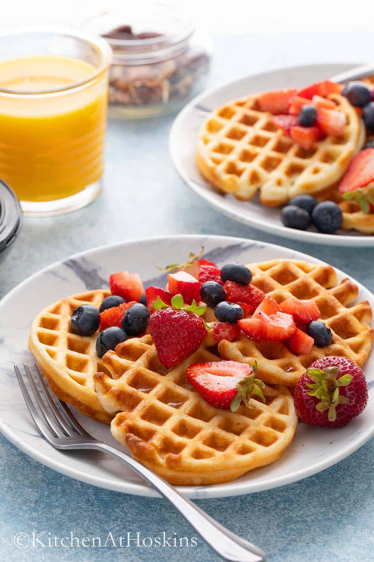 2 round plates with mini waffles topped with syrup and a fork.