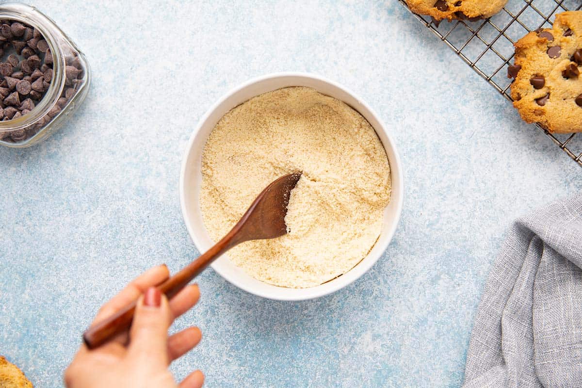 Stirring almond flour, sugar and baking powder in a bowl.