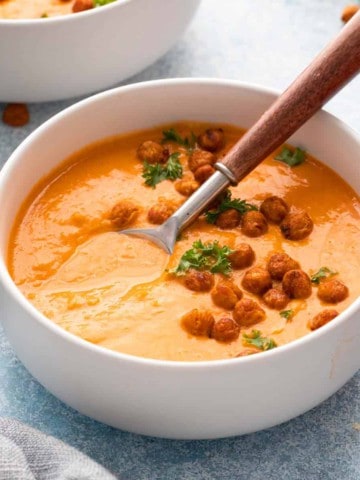 white bowl with creamy chickpea soup along with a spoon.