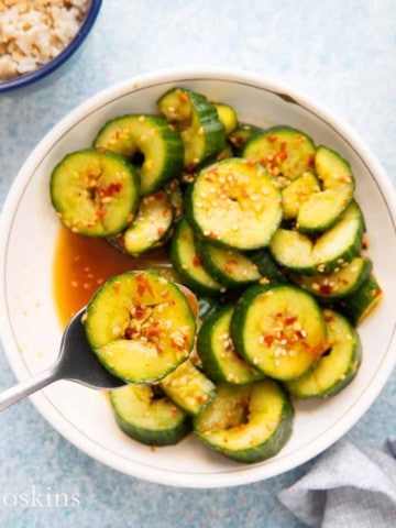 Lifting a Asian marinated cucumber slice with a spoon.