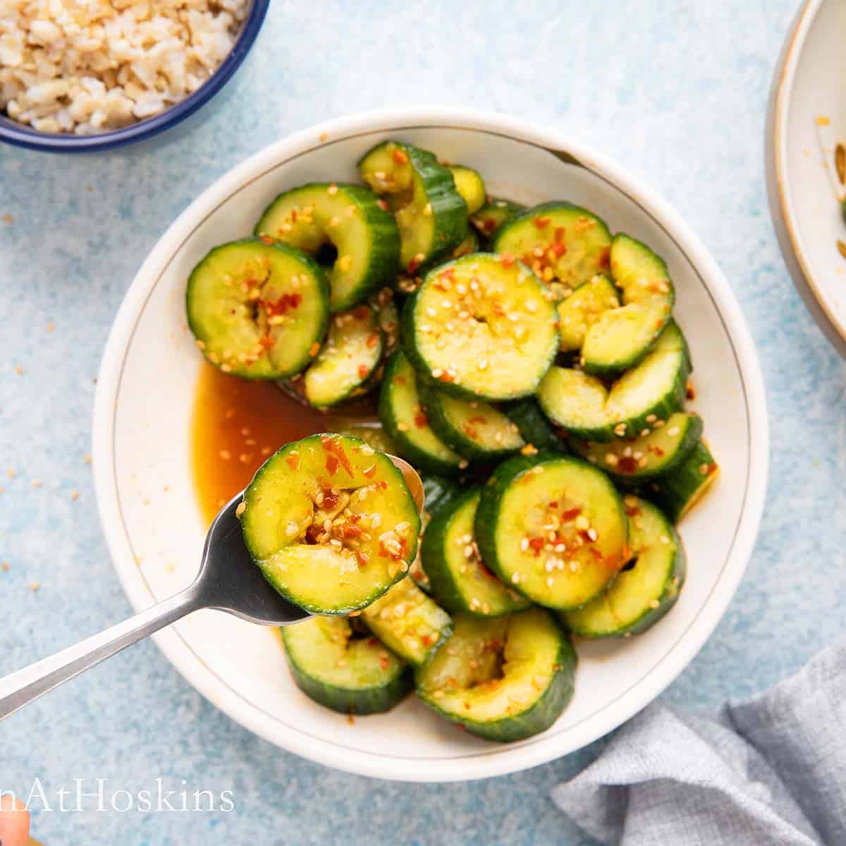 Lifting a Asian marinated cucumber slice with a spoon.