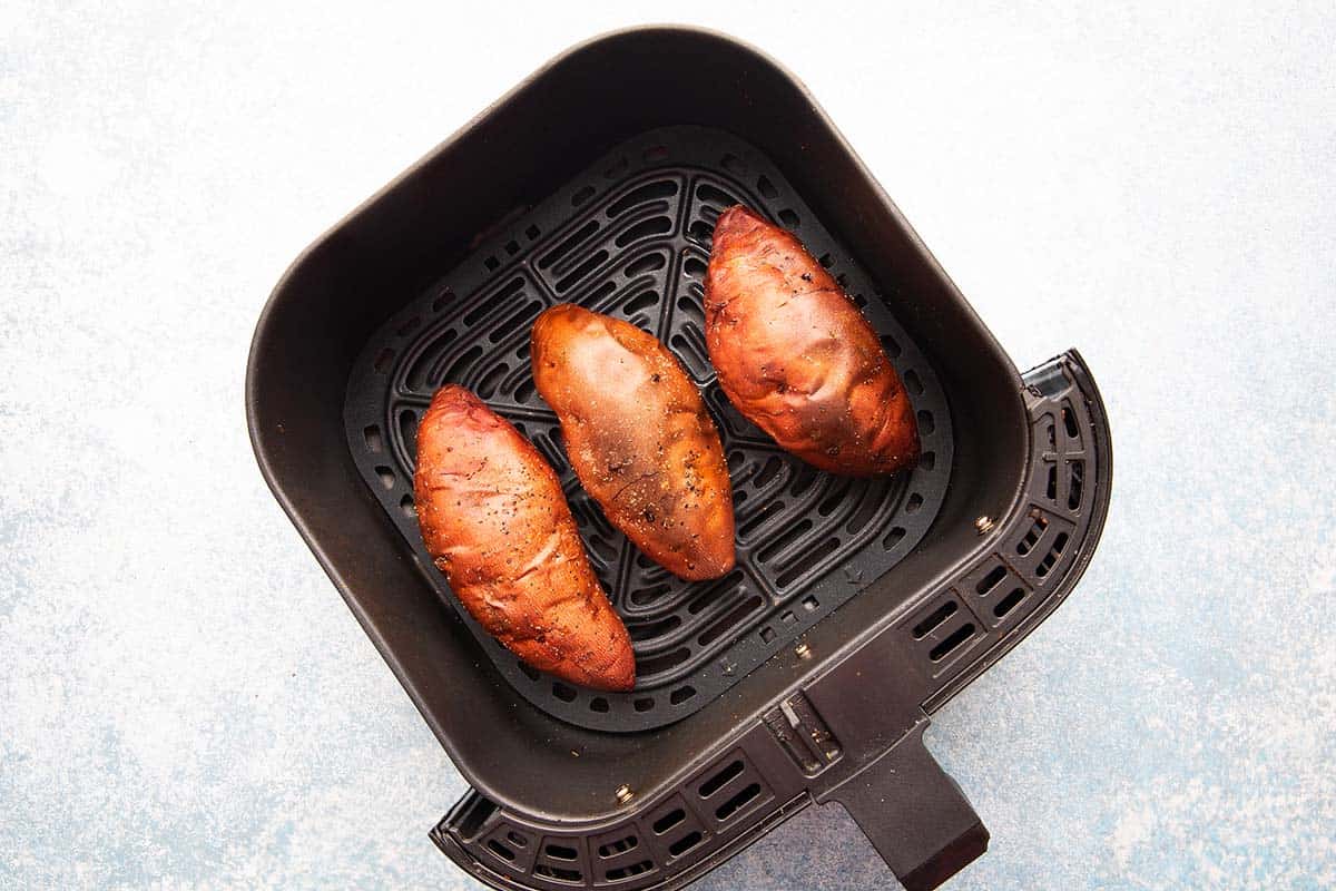 cooked whole sweet potatoes in an air fryer basket.