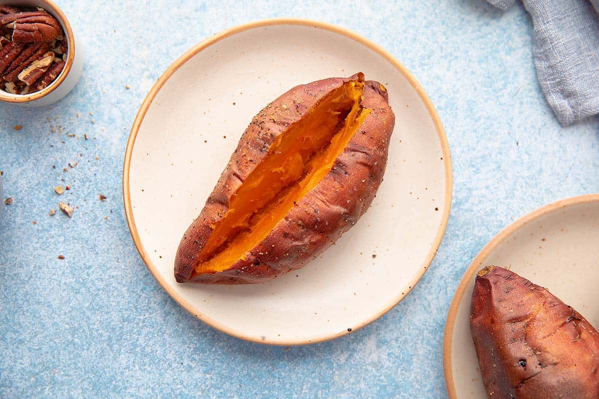 cooked sweet potato split open on a round plate.