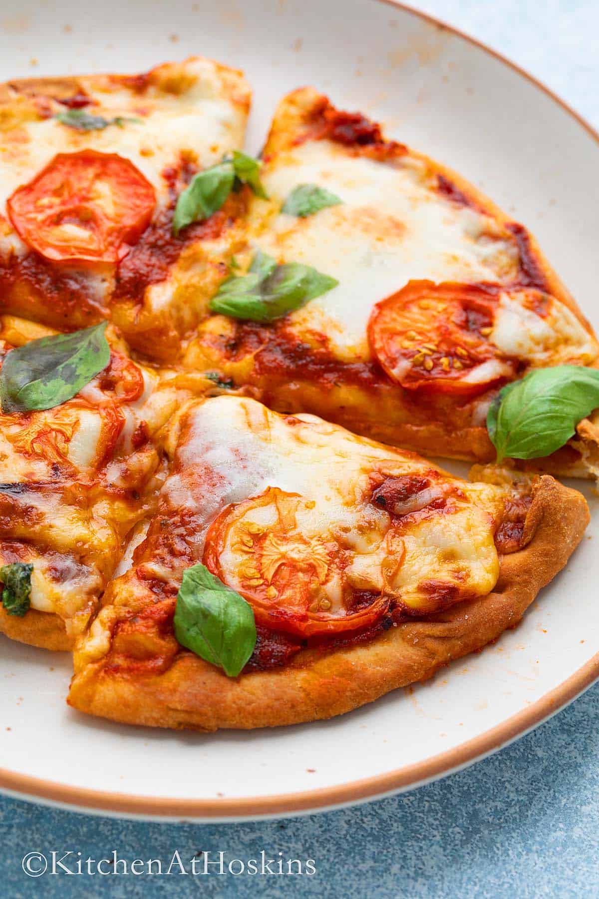 white plate with small pizza garnished with basil.