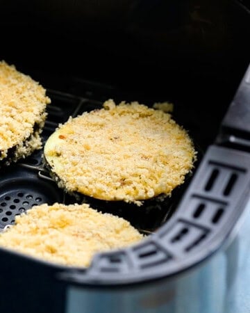 3 breaded eggplant slices in an air fryer basket.