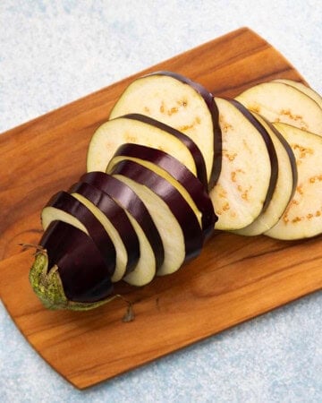 cut eggplant slices on a wooden cutting board.