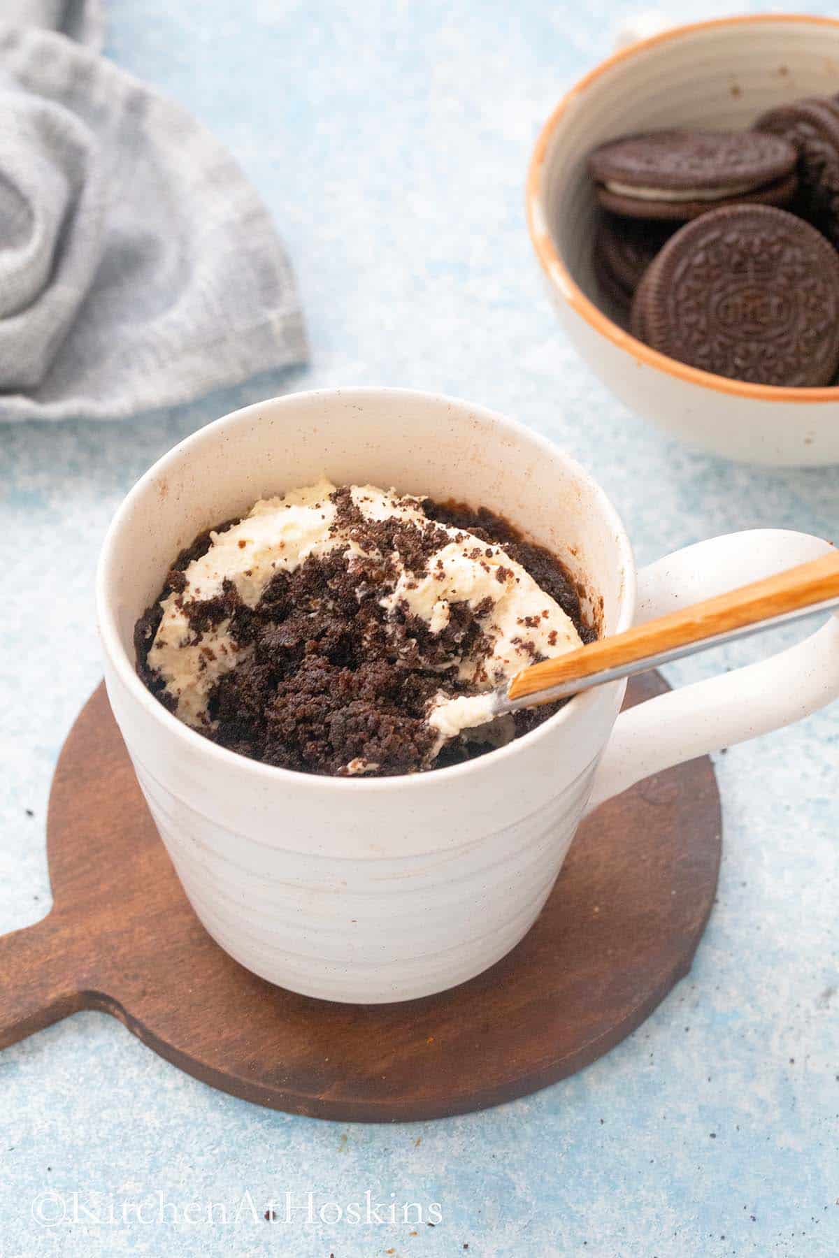 chocolate cake made with oreos in a mug and a spoon.