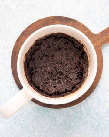 cooked black oreo mug cake in a white mug.