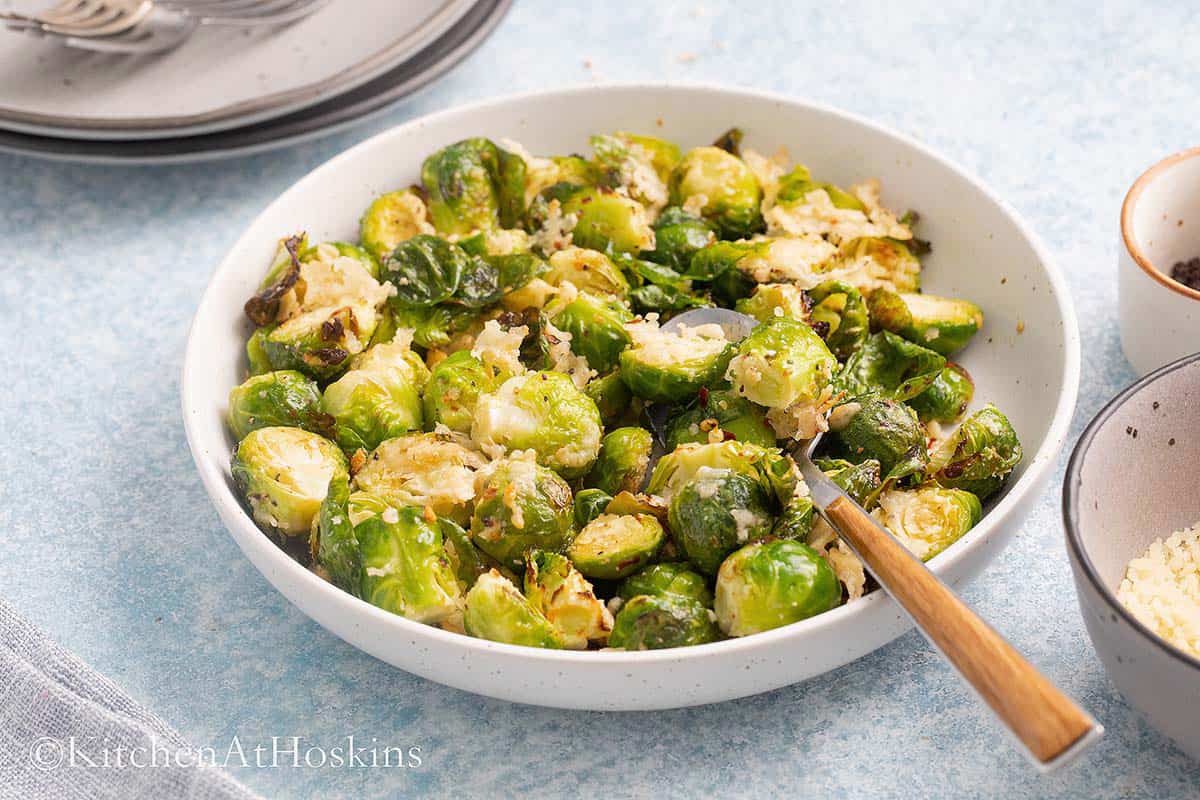 white dish with roasted brussels sprouts with parmesan cheese.