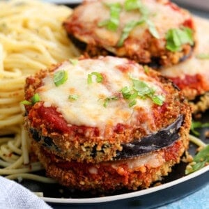 four slices of air fryer eggplant parmesan alongside spaghetti in a black plate.