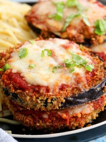 four slices of air fryer eggplant parmesan alongside spaghetti in a black plate.