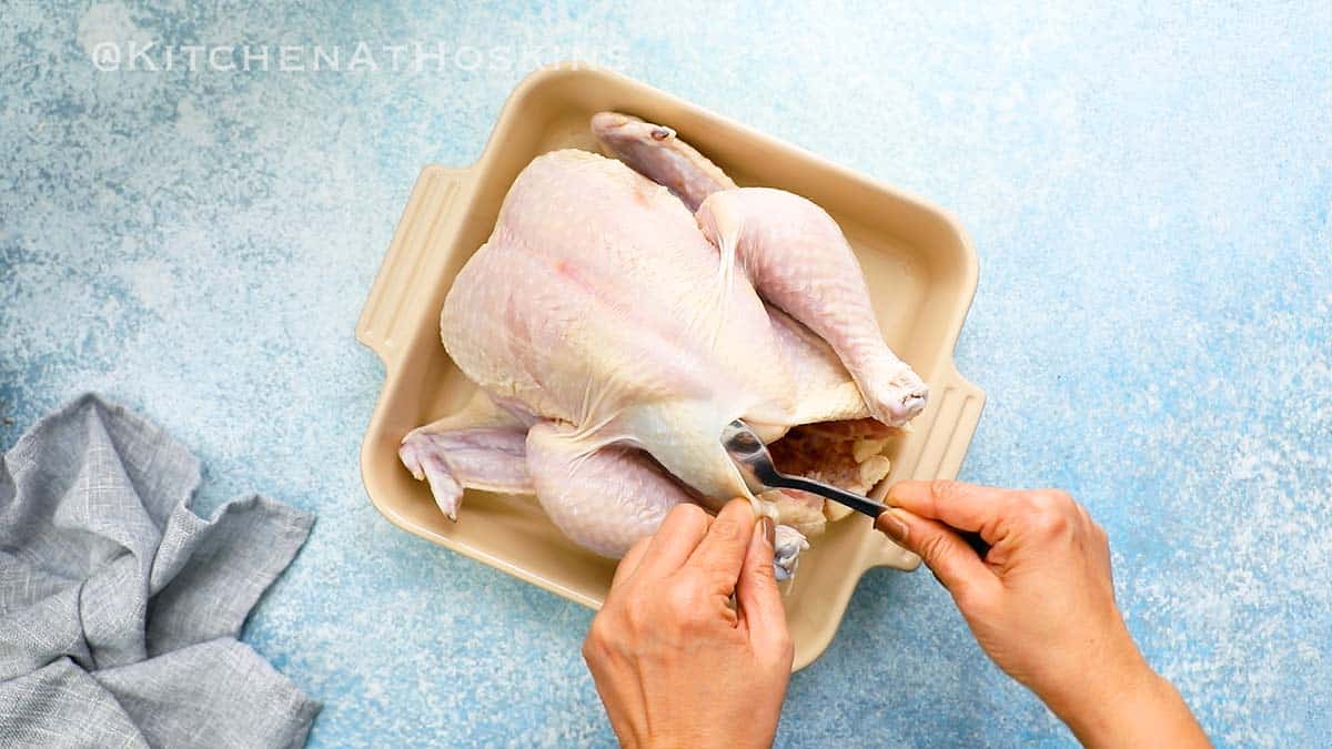 loosening the skin from the breast of a whole chicken with a spoon.