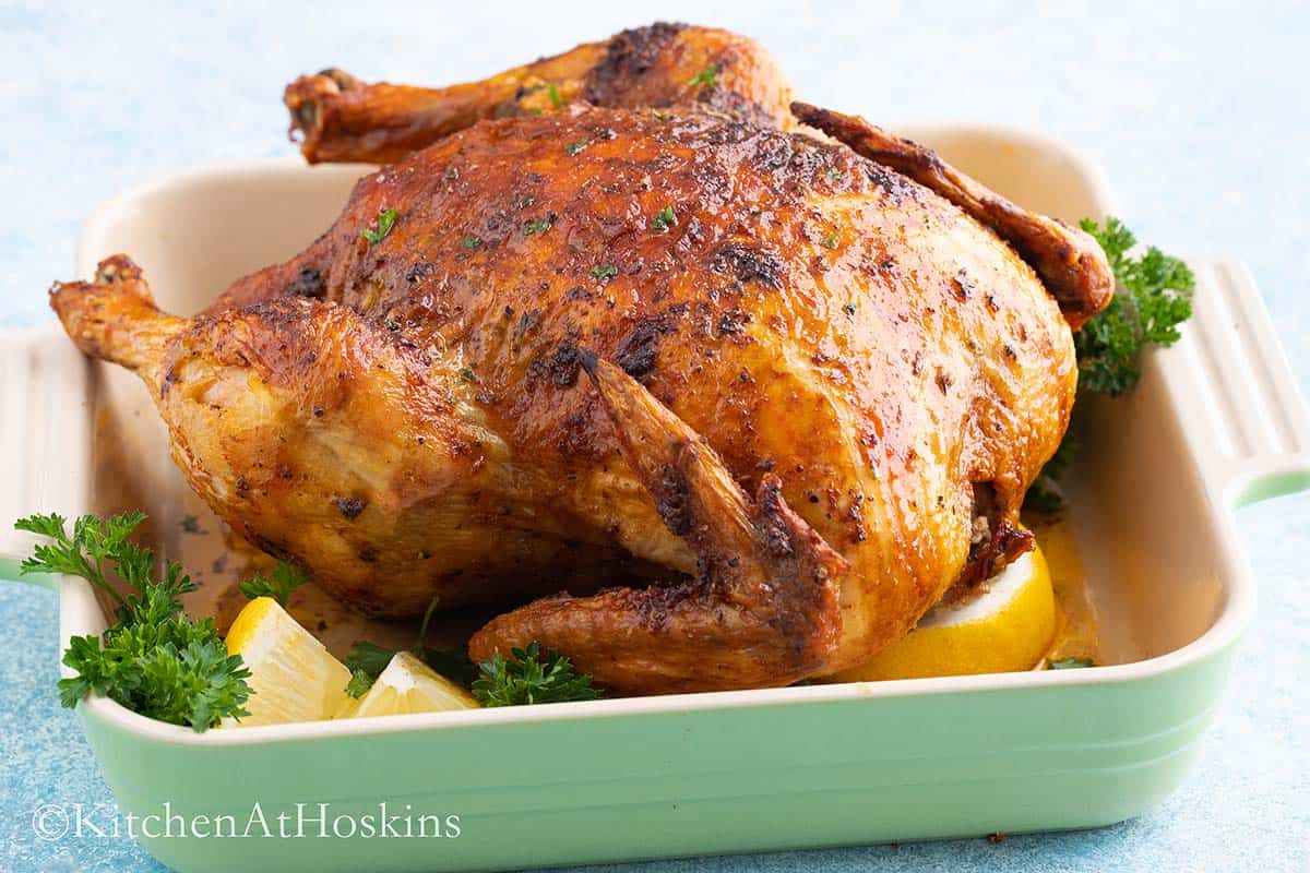 roasted chicken in a green tray with lemon and parsley.