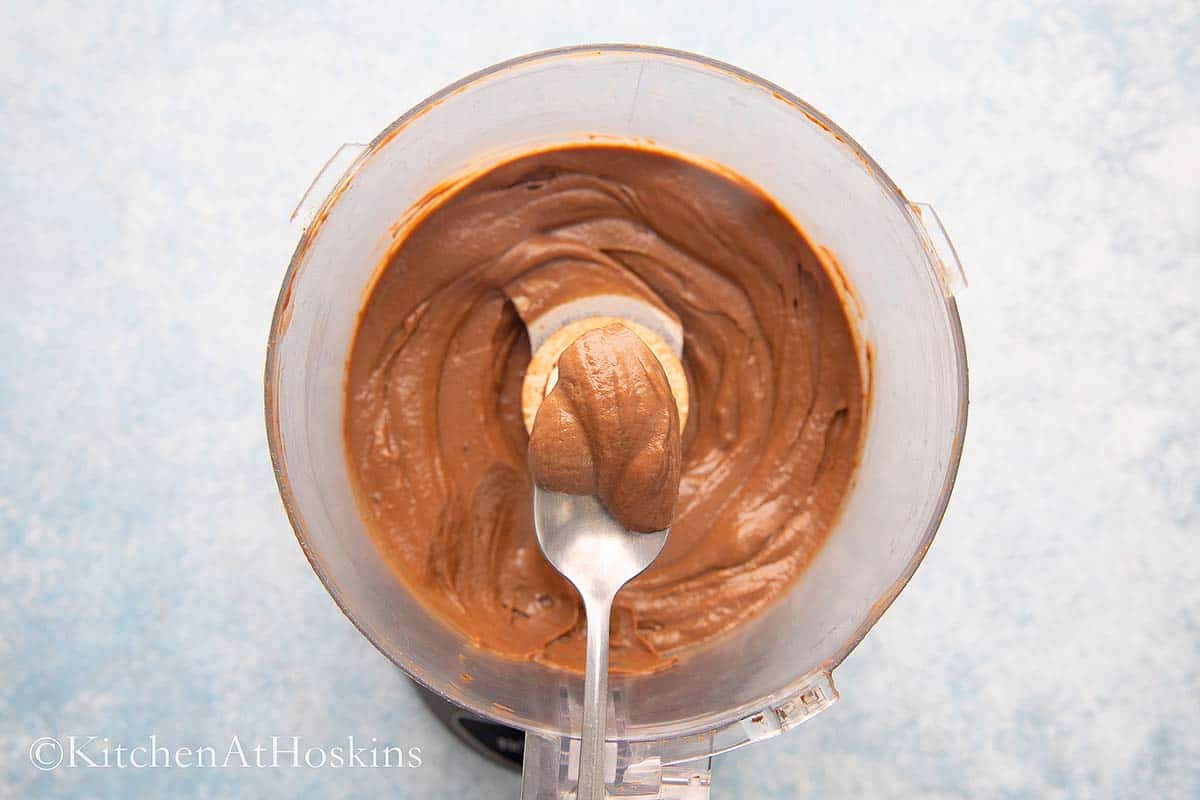 a spoon with creamy chocolate mousse from a processor. 
